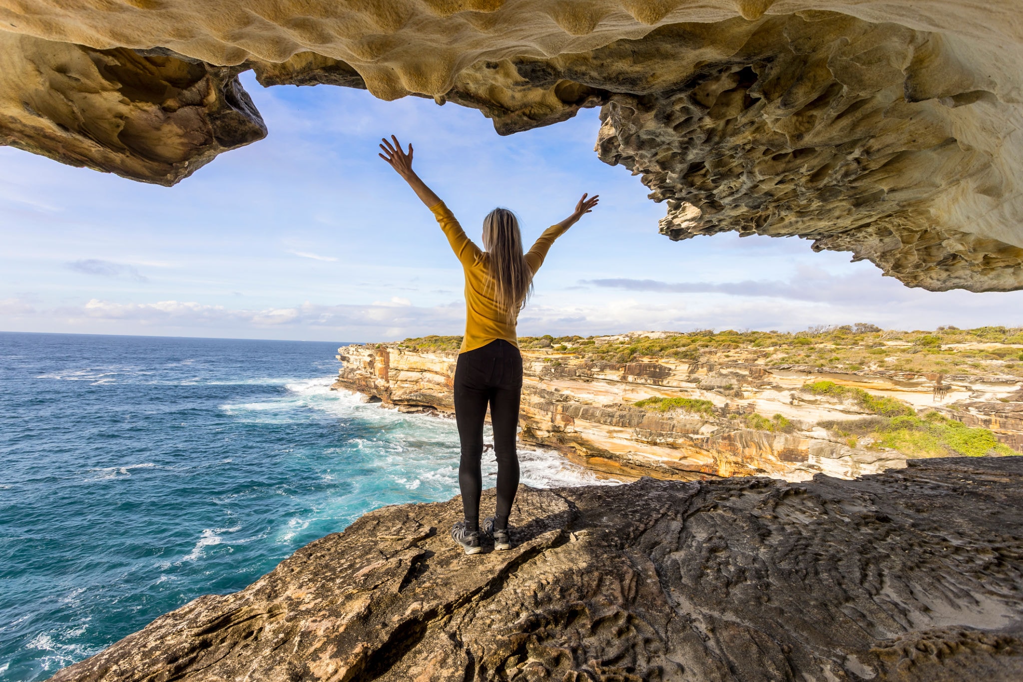 Woman on coastal cliff overlooking turquoise Algarve ocean